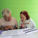 Doli-e-Chico-2 Os primos e professores, Chico Máximo e Dóli de Castro Ferreira. Chico Máximo fez a revisão gramatical. Dóli e o Padre Fabrício Beckmann foram os responsáveis pela pesquisa que resultou no livro Diocese de Lorena - 75 Anos de História. Na foto, de 2012, discutem os textos do livro.