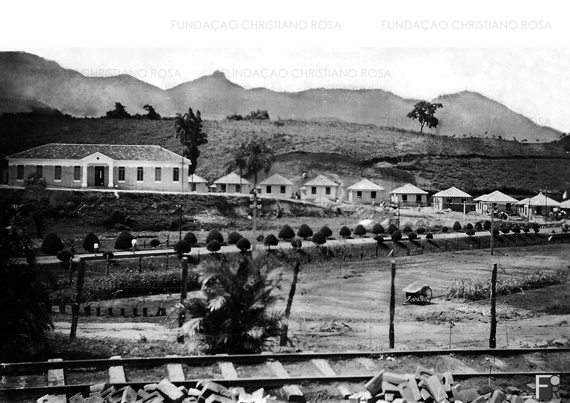Construção em fase final da Vila General Gomes Carneiro. À esquerda, o antigo hospital da Fábrica de Pólvora sem Fumaça, mais tarde farmácia e, atualmente, Fórum de Piquete. Em primeiro plano, os trilhos do ramal férreo.