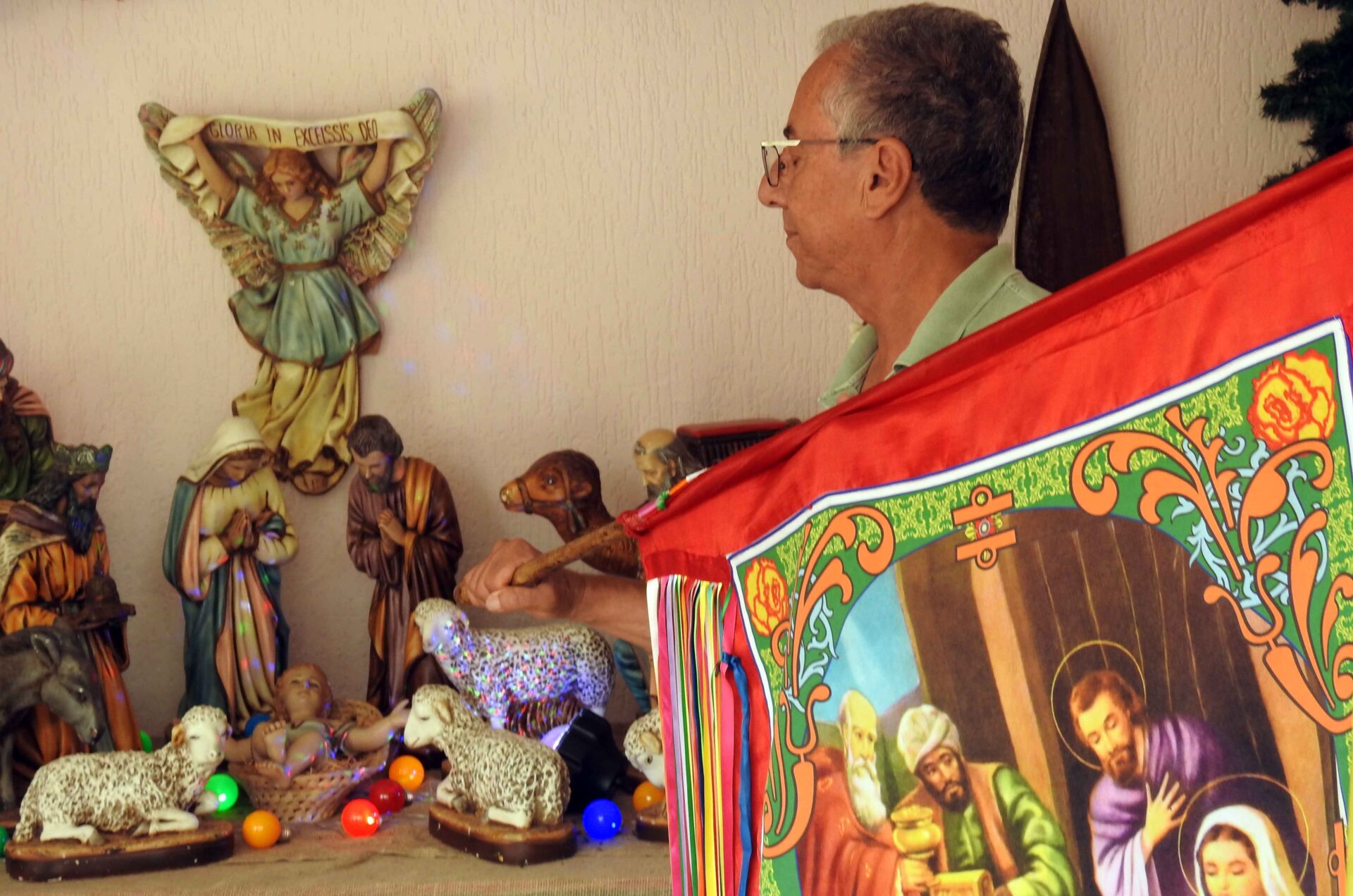 O dono da casa que recebe a Folia segura a Bandeira de Reis enquanto os Foliões cantam.
