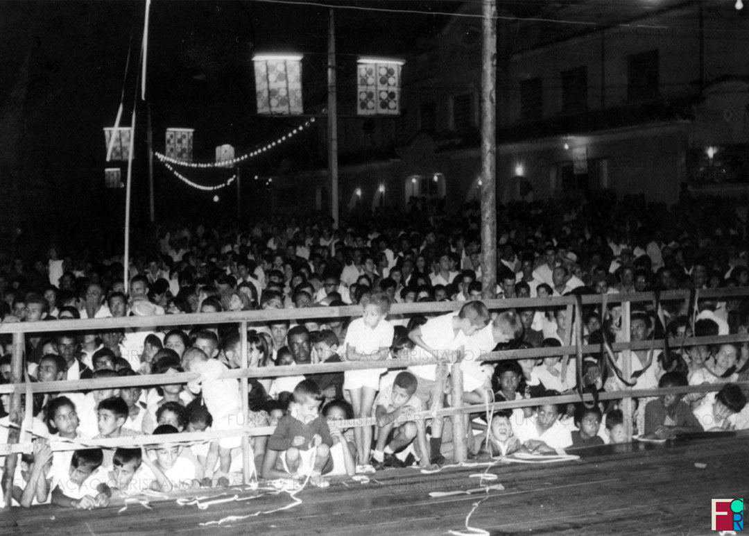 Piquetenses se aglomeram ao lado de passarela armada para desfile de Carnaval na Praça Duque de Caxias, em Piquete, SP. Foto de 1966.