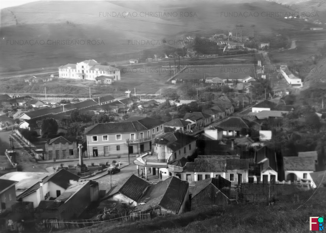 Praça da Bandeira vista do alto do bairro da Caixa D’Água. Observa-se seu traçado original, com o paredão e o pórtico de acesso à Vila Duque, à esquerda. Também na imagem o Bar e Hotel Brasilino e o Posto de Gasolina Caloric. Ao fundo, o Hospital da FPV em fase de conclusão, o Campo do Estrela, a Vila Militar e o trem próximo à Estação da Estrela.