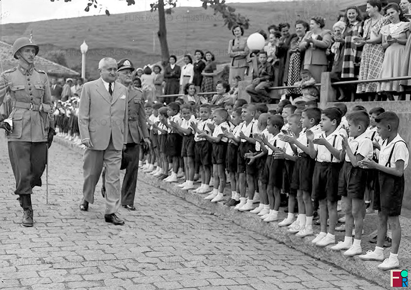 Após inaugurar o Hospital da FPV, o Presidente Eurico Gaspar Dutra, juntamente com o Gen. Waldemar Brito de Aquino, Diretor da FPV, chega ao Cassino dos Oficiais, na Vila da Estrela, sendo recebido por alunos de escolas de Piquete. Foto de 28 de agosto de 1948.