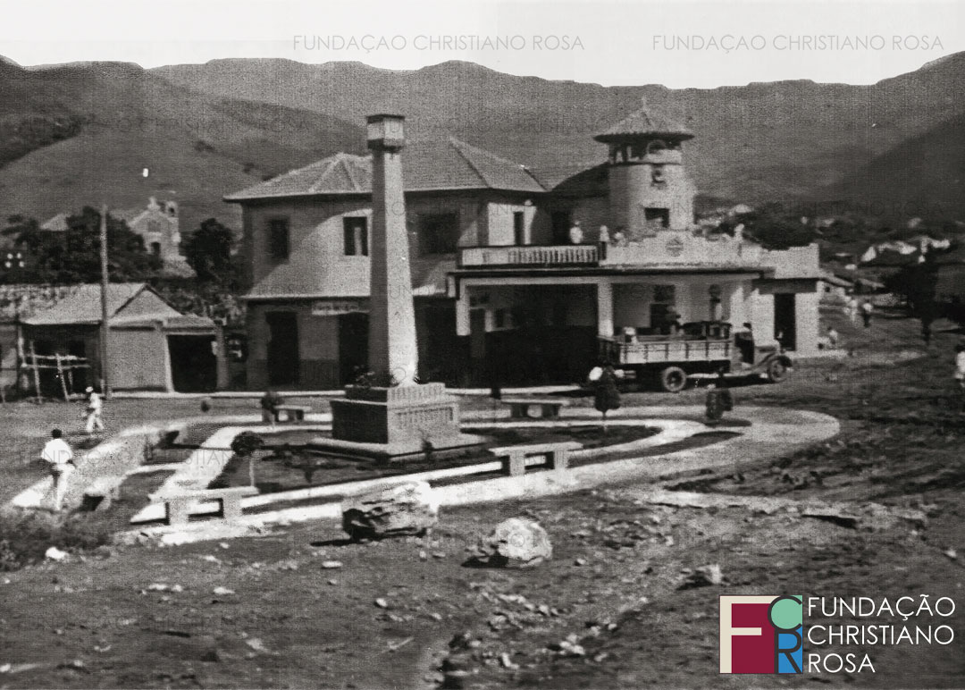 A Praça da Bandeira, vista a partir do alto do paredão que a delimitava originalmente. Observam-se as ruas sem calçamento, padaria bar e posto de gasolina, construídos em 1940 por Miguel Purcino Ferreira. Ao fundo, a Igreja São José, também inaugurada em 1940.