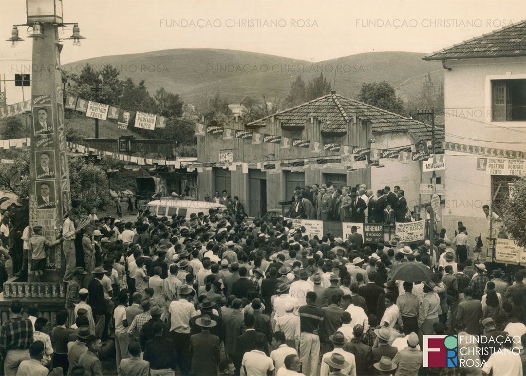 Grande comício de Adhemar de Barros, candidato ao governo de São Paulo, em 1962. Na foto, o caminhão-palanque com o candidato sentado e apoiadores. Ao fundo, o pórtico de acesso à Vila Duque e o ponto de charrete.