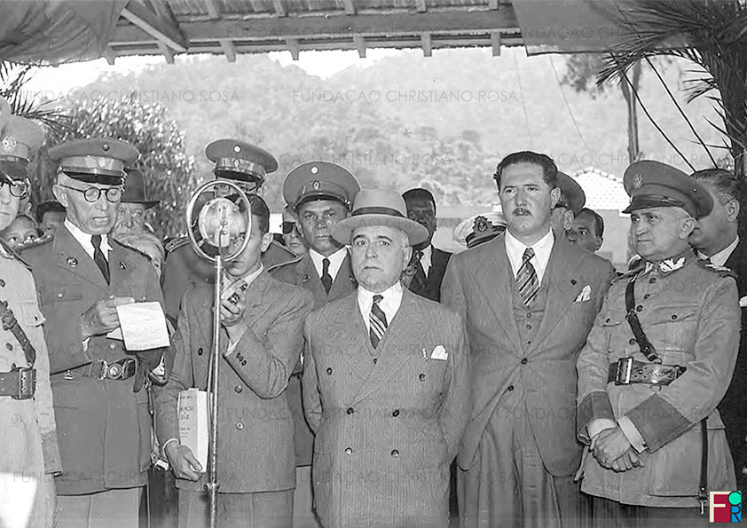 O Coronel Gomes Carneiro, Diretor da Fábrica de Piquete, discursa para o Presidente da República, Getúlio Vargas, que tem ao seu lado o Governador do estado de São Paulo, Adhemar de Barros, e do seu Ministro da Guerra, General Eurico Gaspar Dutra. Foto de17 de julho de 1939.