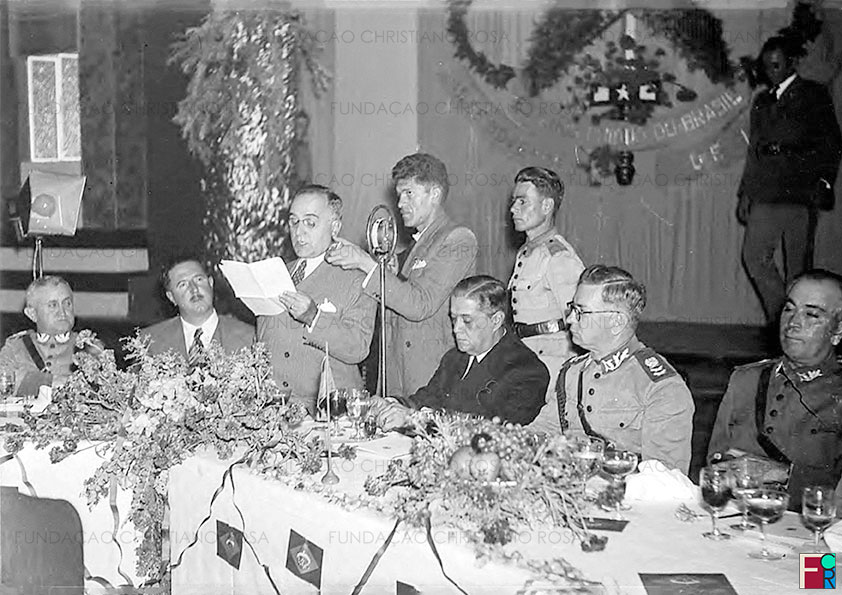 O Ministro da Guerra, general Eurico Gaspar Dutra, ao lado do governador do estado de São Paulo, Adhemar de Barros, ouve o discurso do Presidente Getúlio Vargas, no Cassino dos Oficiais, quando de sua visita à Fábrica de Piquete, em 17 de julho de 1939.